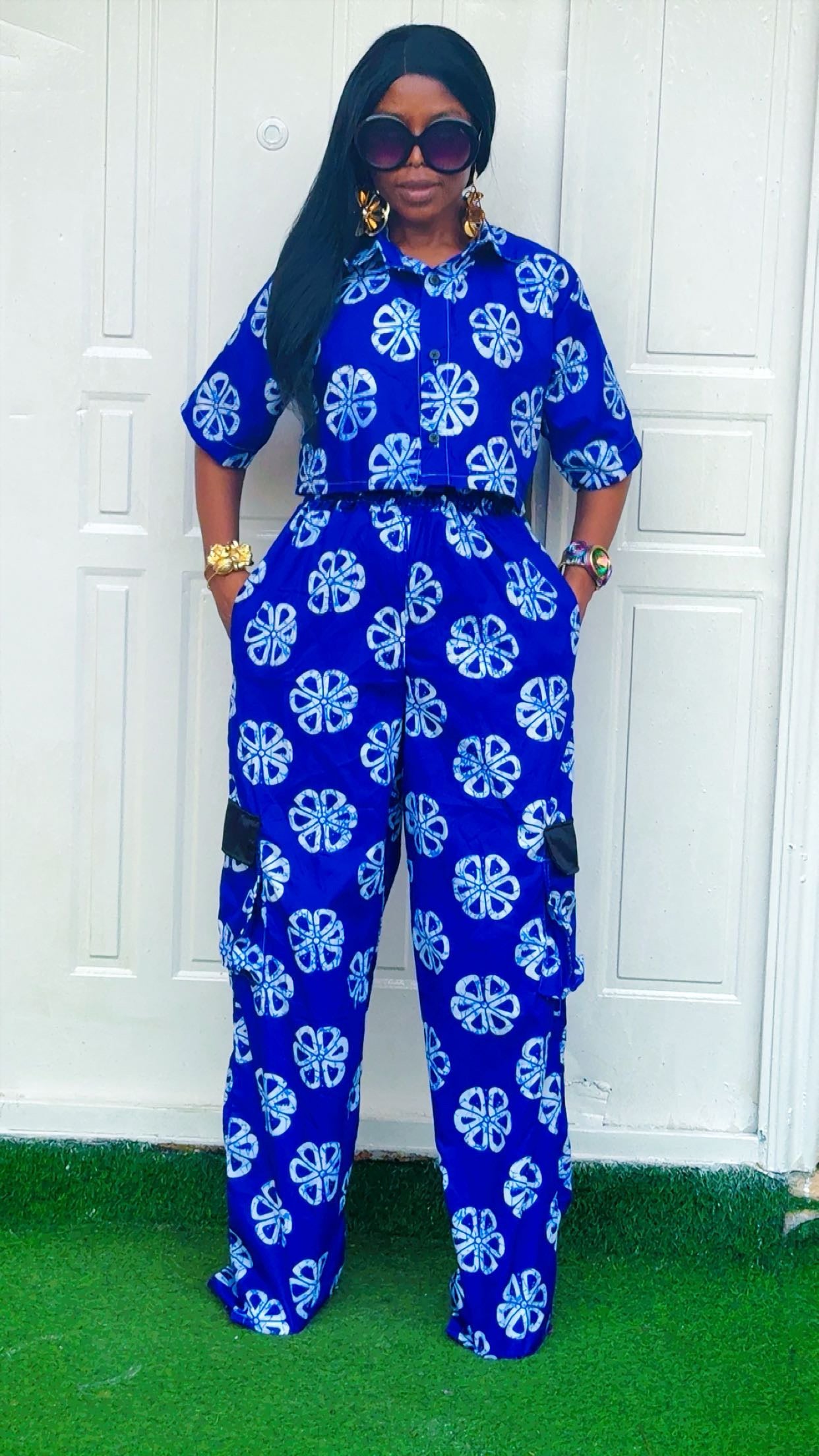 Woman wearing a blue and white floral jumpsuit standing against a white wall.