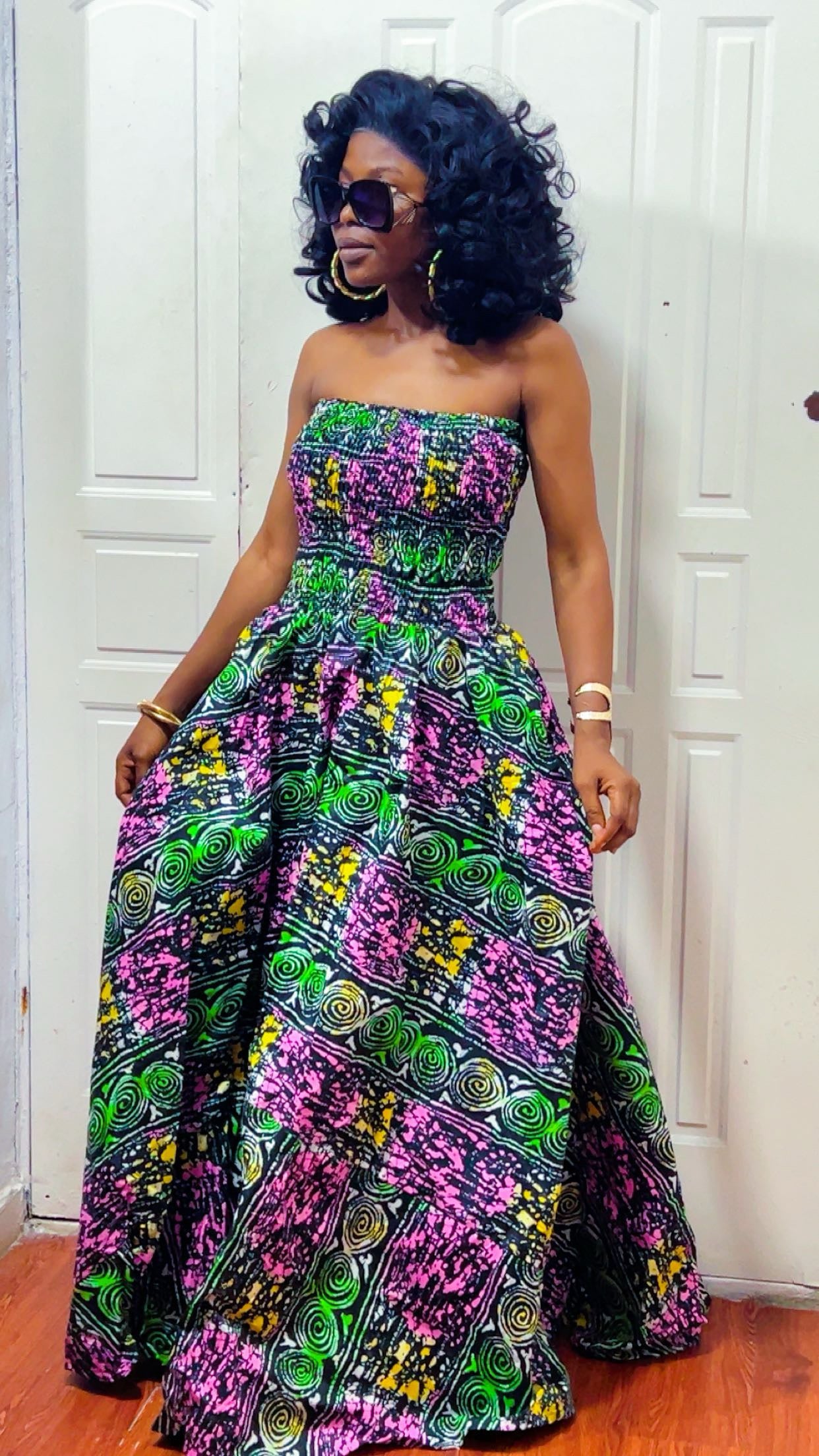 Woman wearing a colorful strapless dress with a pattern in a room.