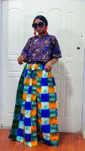 Woman wearing a colorful outfit with a patterned top and checkered pants in a room.