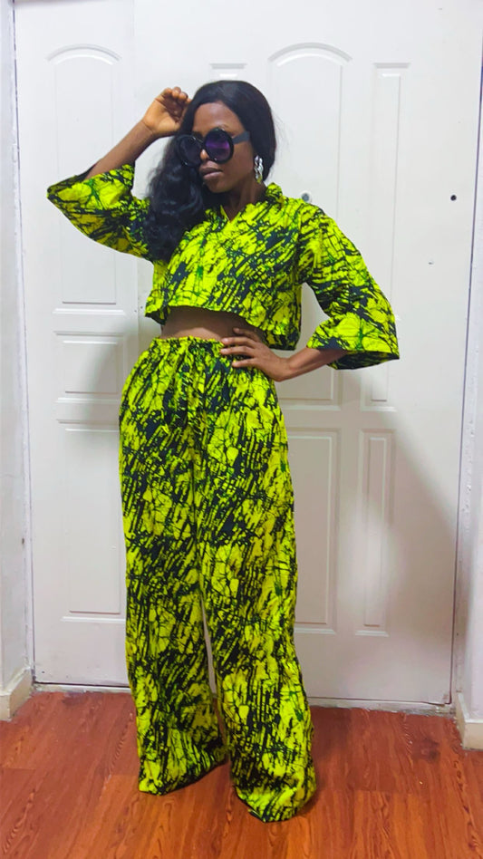 Person wearing a bright yellow and black patterned outfit in front of a white door.